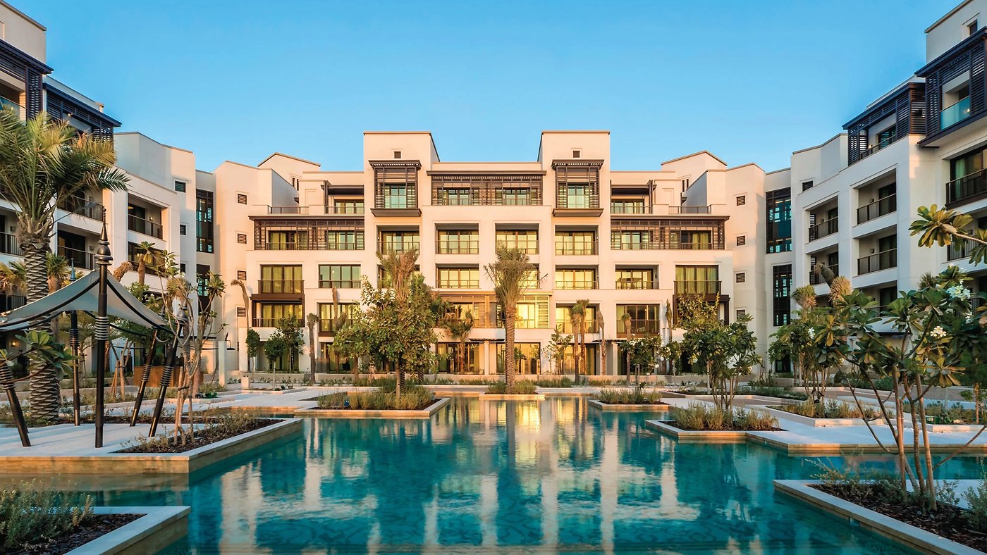 The courtyard pool at Jumeirah Al Naseem at dusk, with the shuttered facades lit from within