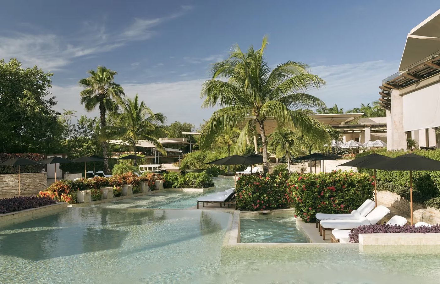 The terraced pools at Rosewood Mayakoba on the Riviera Maya, shaded by palms and parasols