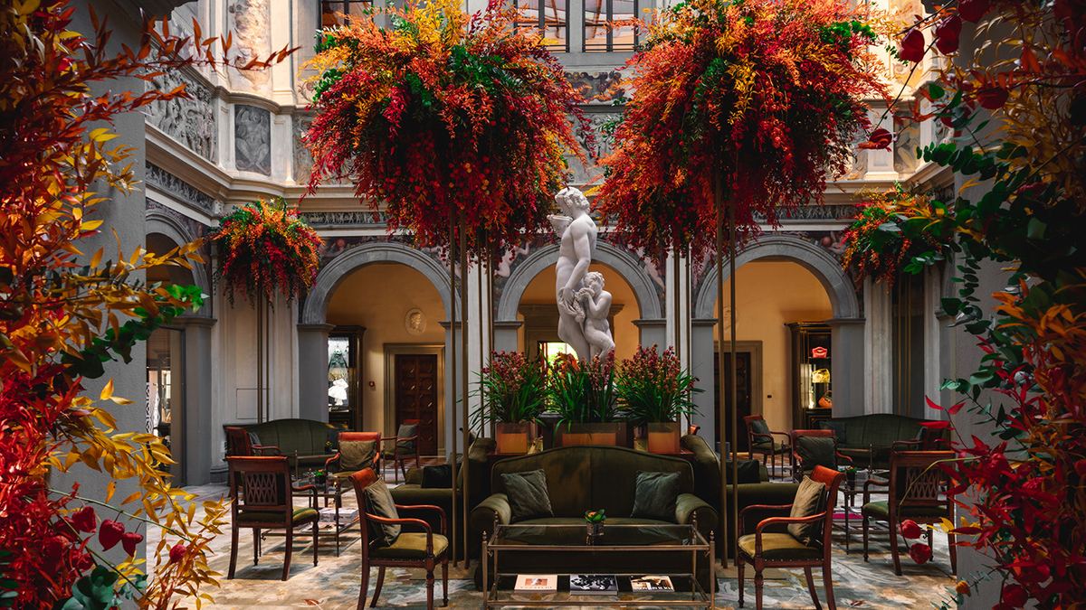 The frescoed atrium of Four Seasons Hotel Firenze, with a marble sculpture and suspended floral installations