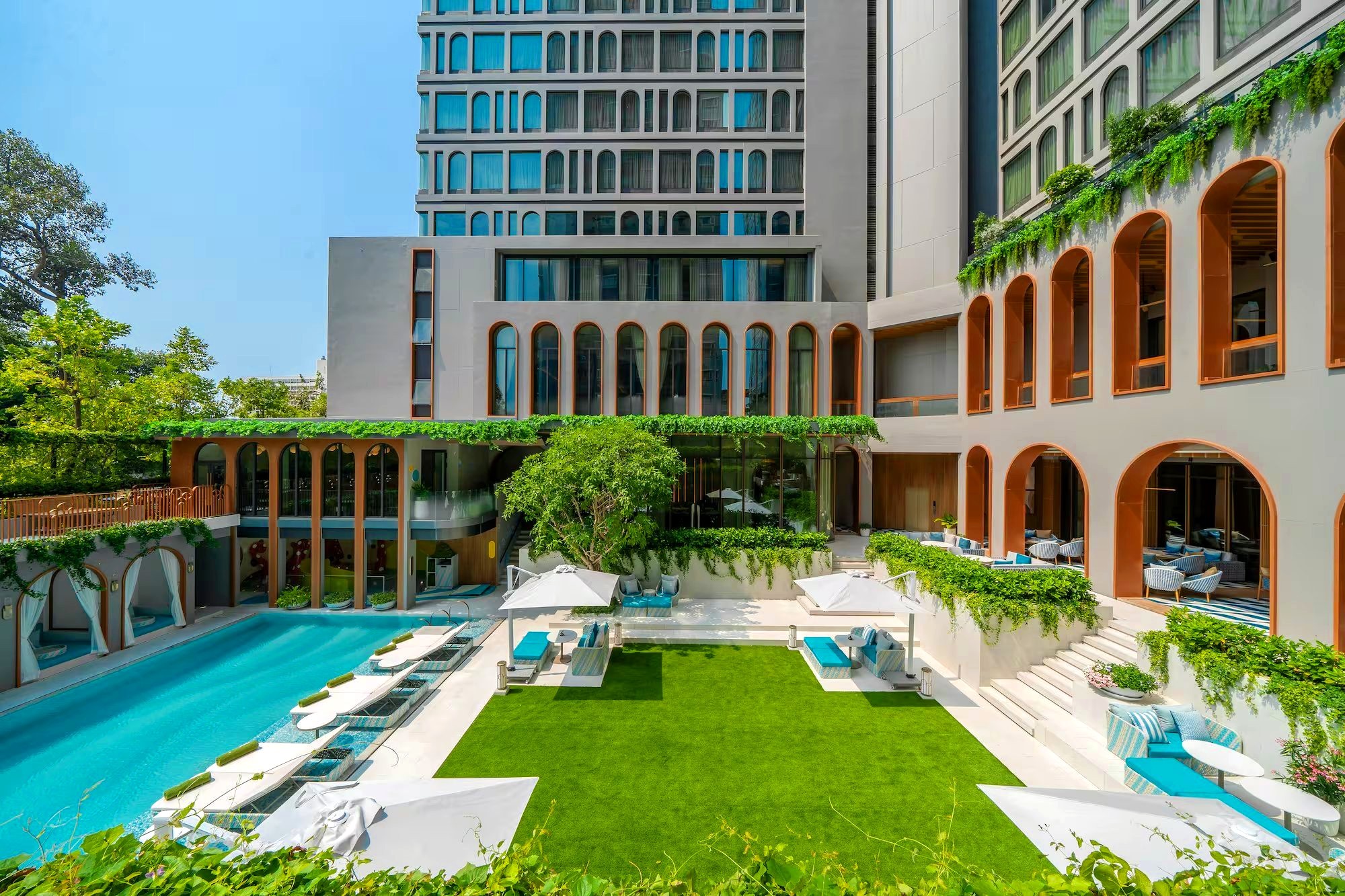 Rooftop pool and lawn terrace framed by arched windows
