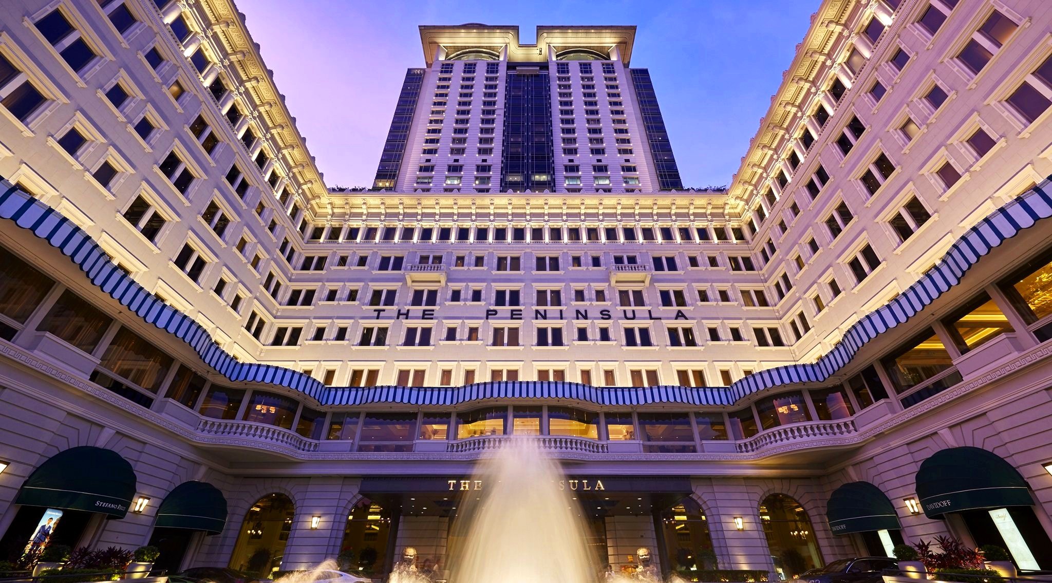 The Peninsula Hong Kong facade lit at dusk with its fountain courtyard