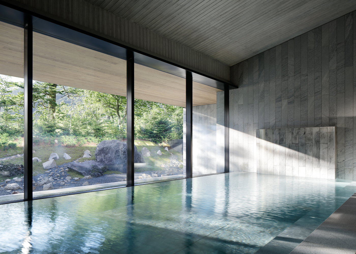 The indoor onsen bath at The Ritz-Carlton Nikko, floor-to-ceiling glass onto a rock garden and forest