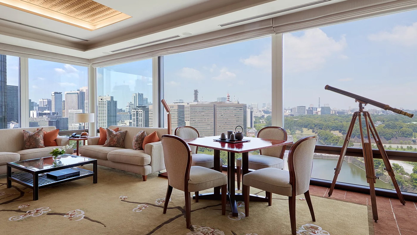 A guest room at The Peninsula Tokyo with a brass telescope at the window, looking over the Imperial Palace moat and gardens