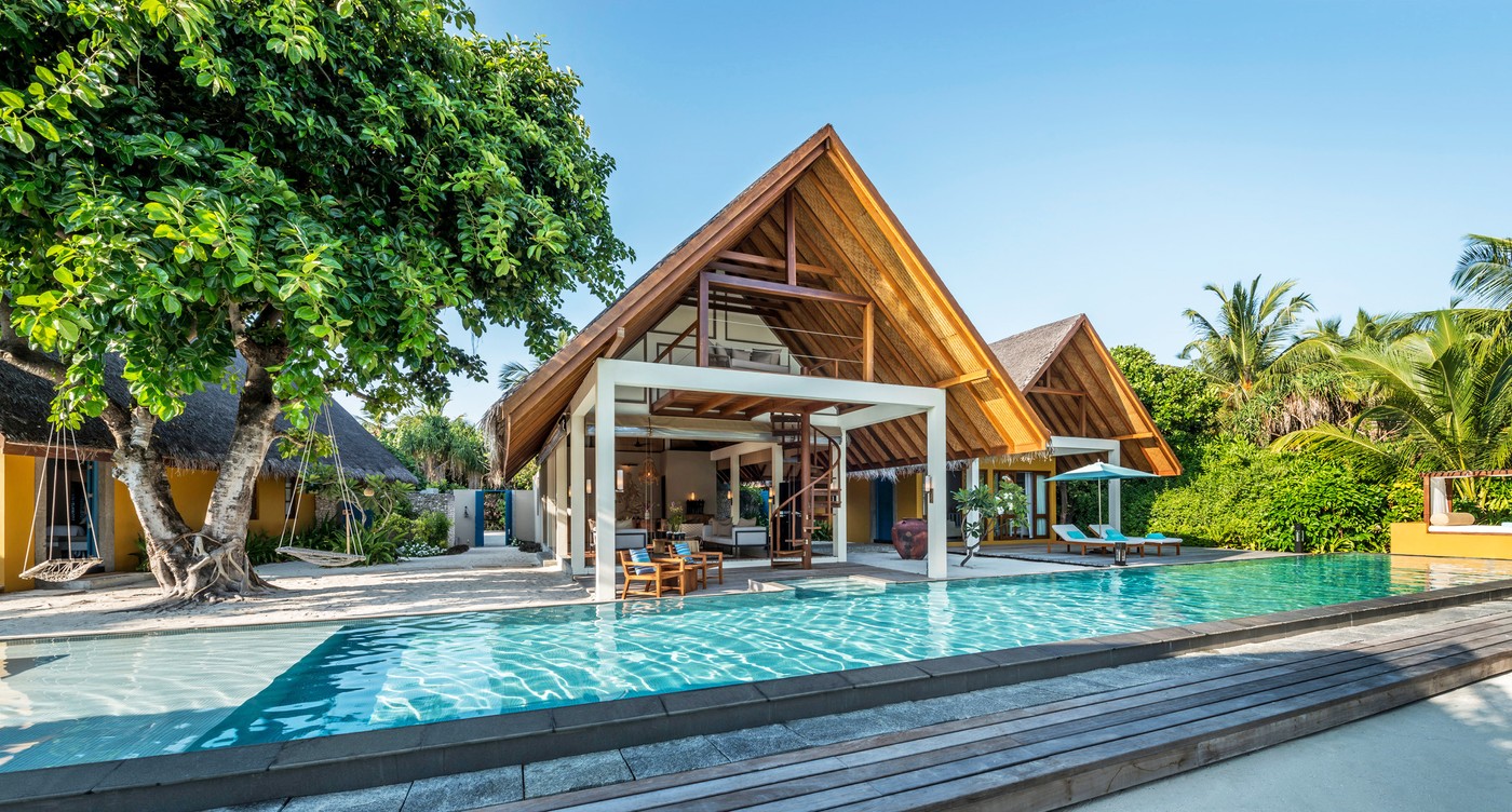 A beach villa at Four Seasons Landaa Giraavaru, its pool running the length of the deck beneath a banyan