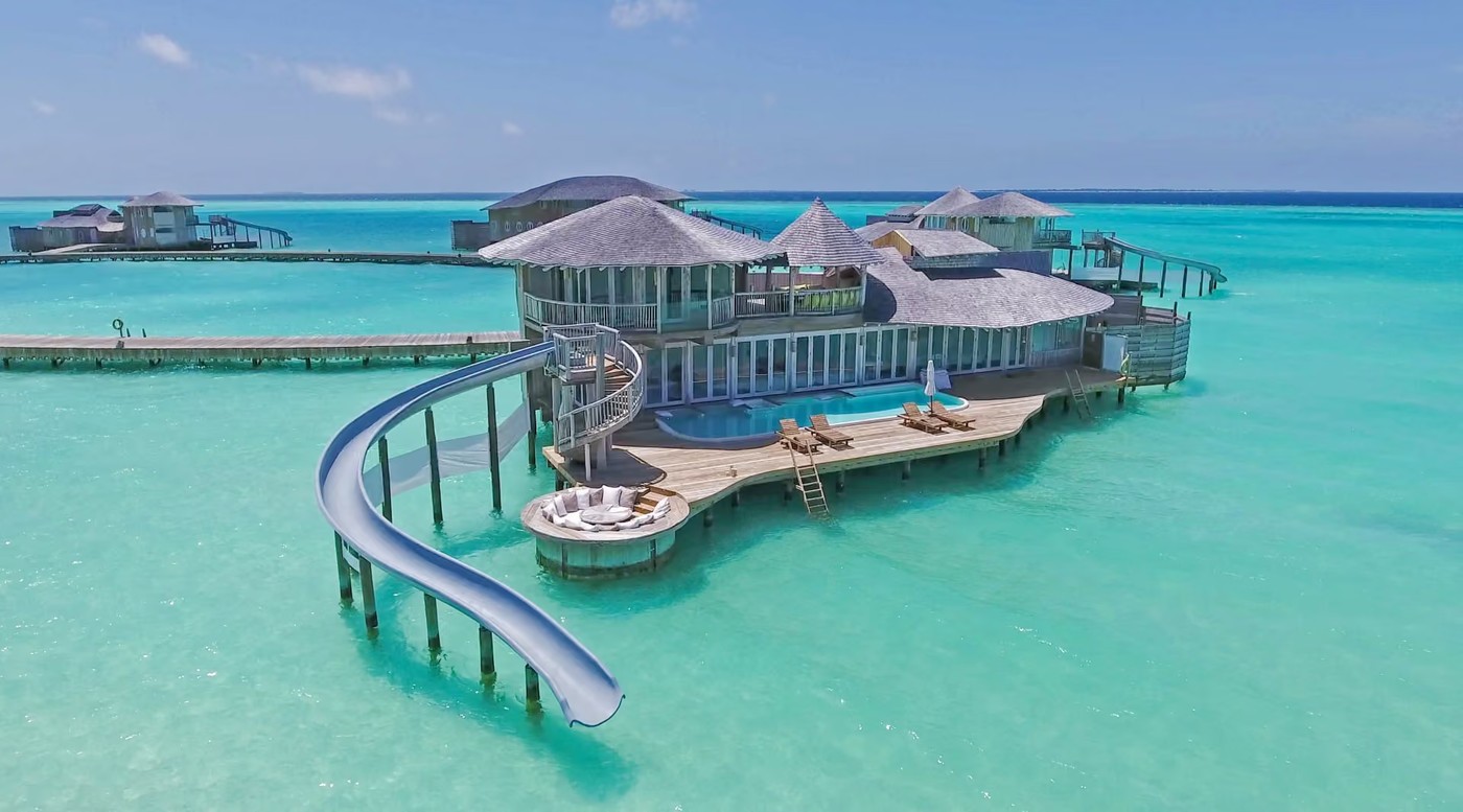 An overwater villa at Soneva Jani, the water slide curving from the upper deck into the lagoon