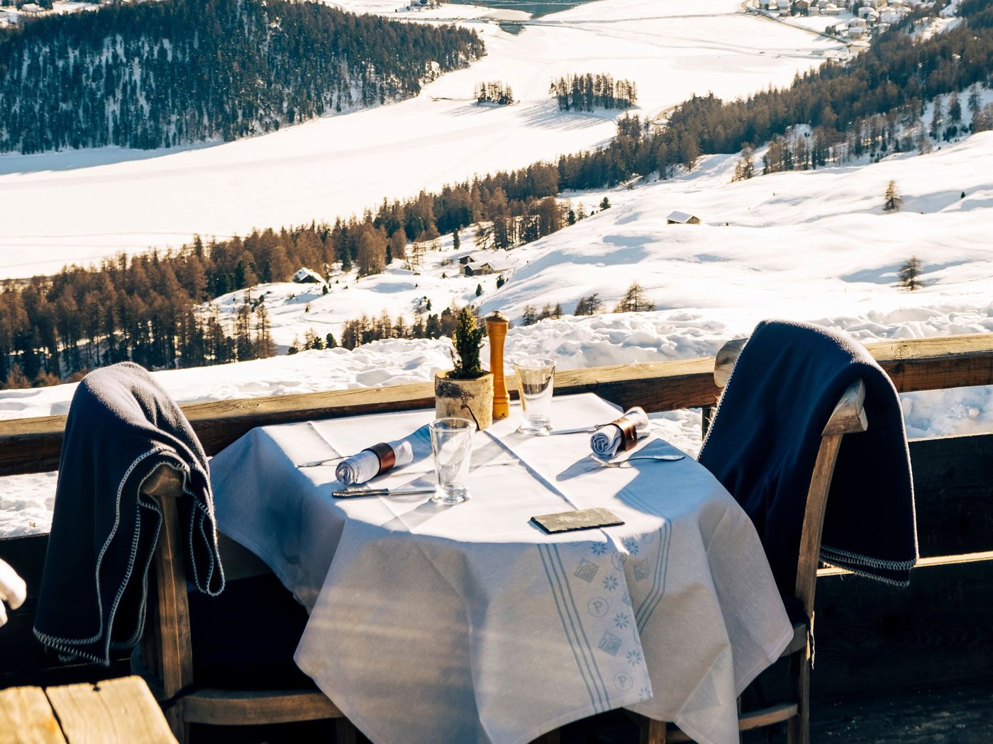 A terrace table above the frozen Engadine lakes, blankets laid over the chairs
