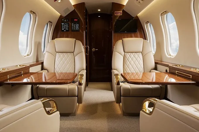 The cabin of a private jet, facing seats either side of a folding table