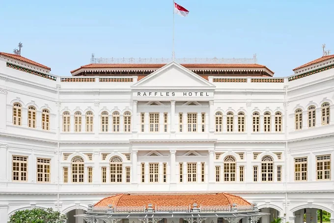 The colonial facade of Raffles Hotel Singapore behind its palms