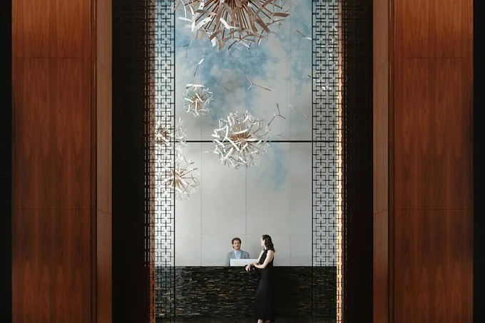 Two guests seated in a hotel lobby beneath a sculptural artwork