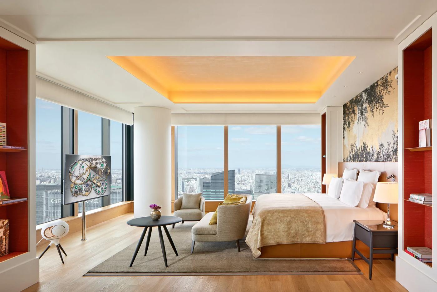 A Bulgari Tokyo room with floor to ceiling windows over the city, red lacquer shelving and a gilded screen